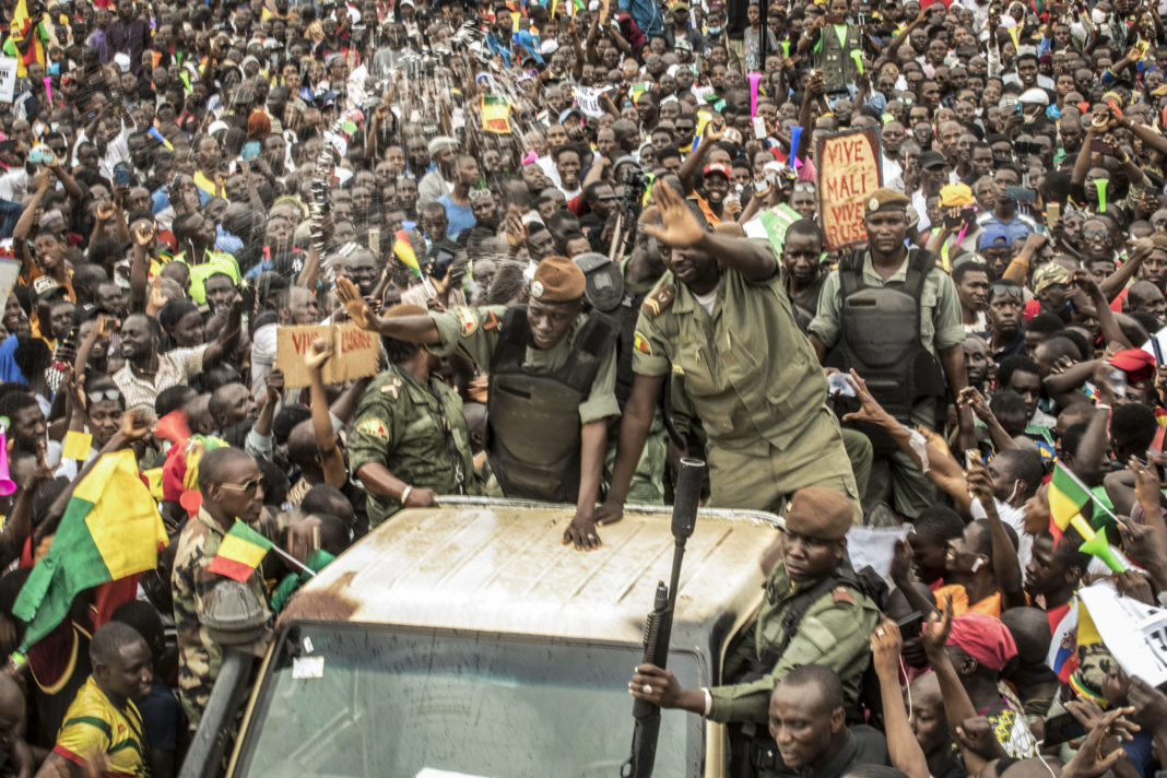 An unidentified representative of the junta waves from a military vehicle as Malians supporting the recent overthrow of President Ibrahim Boubacar Keita gathers to celebrate in the capital Bamako, Mali, on Aug. 21, 2020.