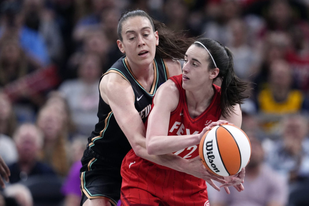 Indiana Fever's Caitlin Clark, right, makes a pass as New York Liberty's Breanna Stewart, left, defends during the first half of a WNBA basketball game in Indianapolis on Saturday.