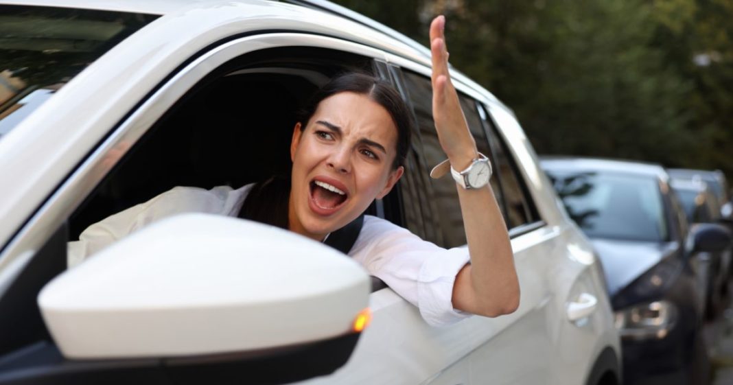 This image shows an angry female driver screaming at someone in a traffic jam.