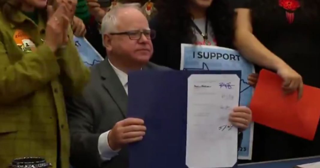 Minnesota Gov. Tim Walz holds up a bill he signed that will allow anyone in the state to receive their driver’s license, regardless of their immigration status.