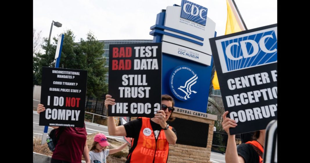 People hold signs at a protest against masks, vaccines, and vaccine passports outside the headquarters of the Centers for Disease Control (CDC) on March 13, 2021 in Atlanta, Georgia.