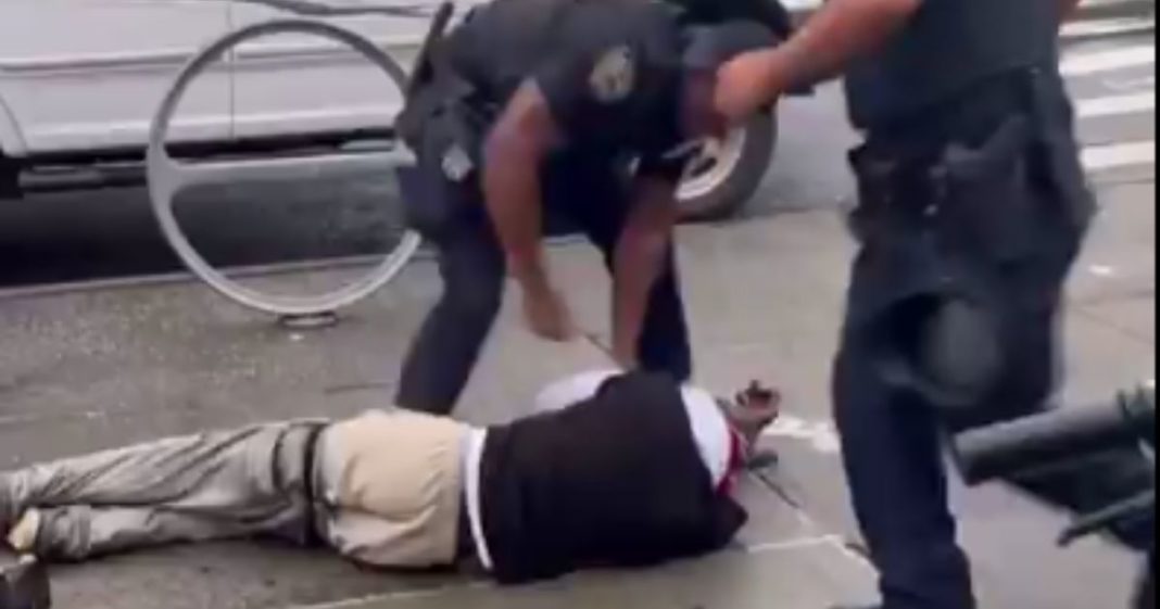 A New York police officer stands over a man that allegedly hit his partner, a female, as she was trying to break up a disturbance between the man and a group of kids.