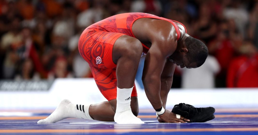 Mijain Lopez Nunez of Team Cuba removes his shoes to signify his retirement following his victory and earning of fifth Olympic Gold during the Wrestling Men's Greco-roman 130kg Gold Medal match against Yasmani Acosta Fernandez of Team Chile on day 11 of the 2024 Olympic Games Tuesday in Paris