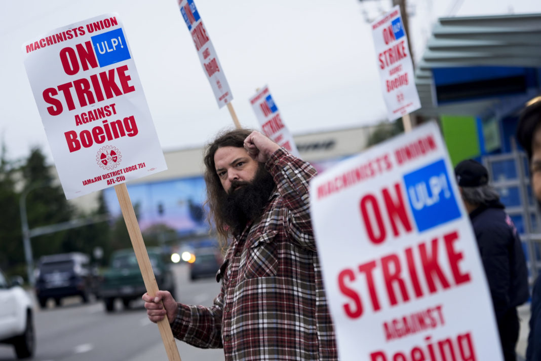 Jacob Bustad, a machinist who has worked for Boeing for 14 years, holds up a fist to passing drivers as union members work the picket line after voting to reject a contract offer and go on strike on Sunday near the company's factory in Everett, Washington.