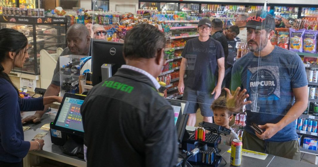 Customers wait in line to purchase items at a 7-Eleven convenience store in Chino Hills, California, on July 28, 2022.