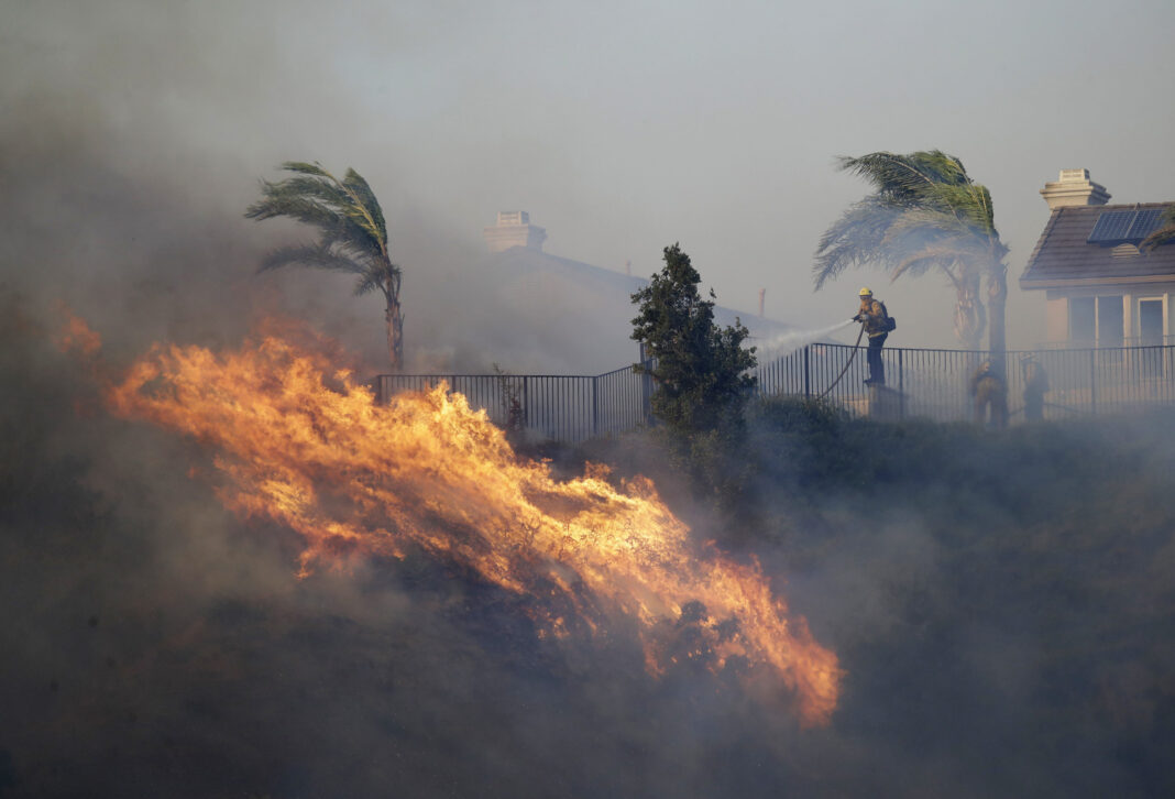 A firefighter sprays water in front of an advancing wildfire in Porter Ranch, California, on Oct. 11, 2019.