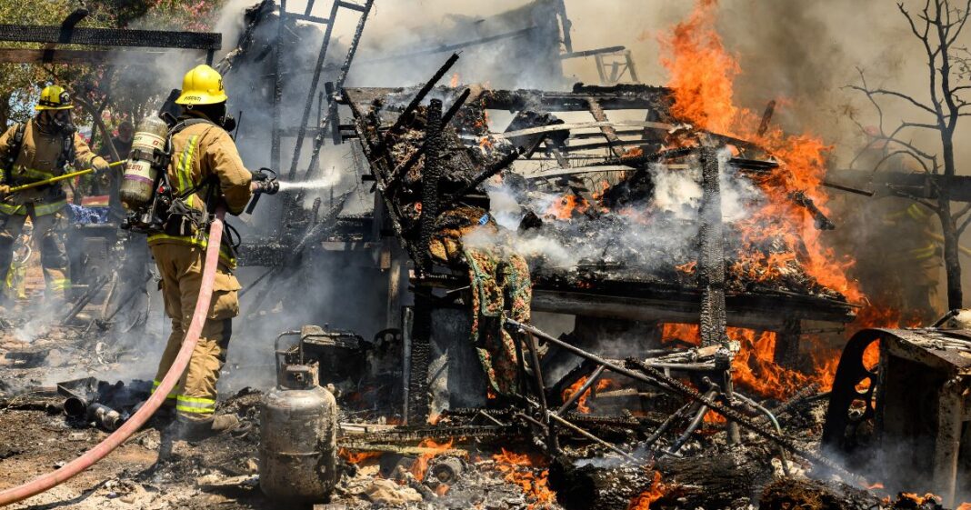 Firefighters knock down a structure fire that ignited from a burning generator and briefly spread to a small spot fire at a home during the Thompson fire in Oroville, California, on July 3.