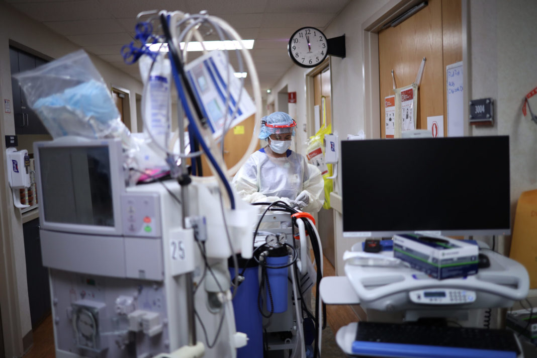 heavily protected health care worker prepares to enter COVID patient's room