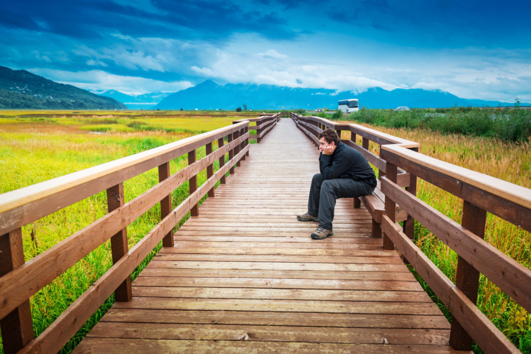 A young man sits on a bench in Potter Marsh in Anchorage in an undated photo. (Photo by LaraBelova/Getty Images)